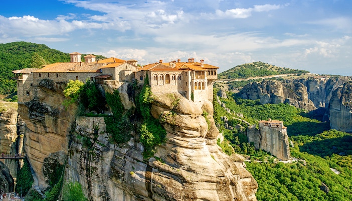 Meteora monastery perched on a rock formation in Greece, surrounded by lush green landscape.