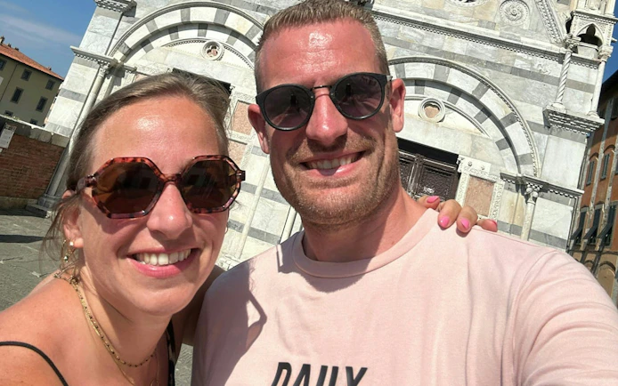 Couple enjoying a self-guided exploration game in front of a historic Pisa building.