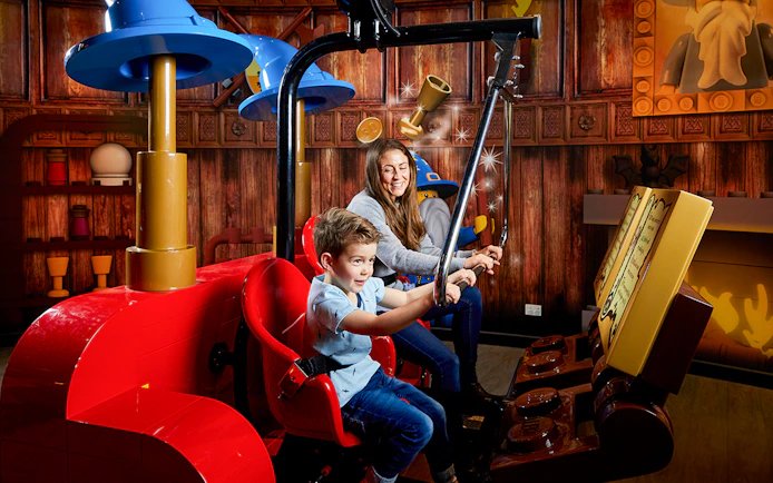 Child and adult enjoying interactive ride at LEGOLAND Discovery Centre.
