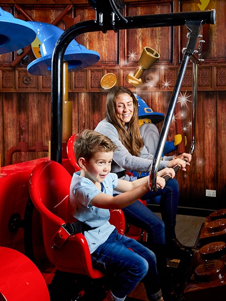 Child and adult enjoying interactive ride at LEGOLAND Discovery Centre.