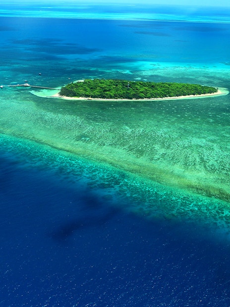 Aerial view of the Great Barrier Reef's outer edges with vibrant coral and clear blue water.