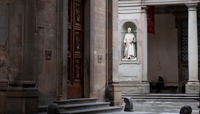Door 3 of the Uffizi Gallery, a quieter entrance edged with historical architecture and a solitary statue overseeing the passage of visitors