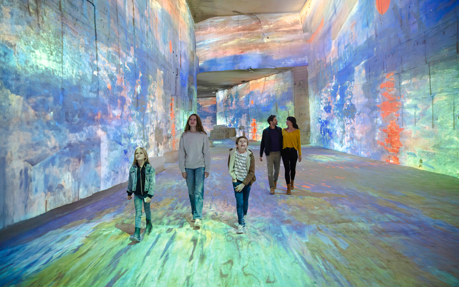 Visitors exploring Monet projections at Carrières des Lumières, France.