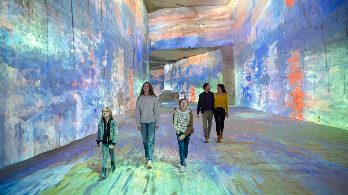 Visitors exploring Monet projections at Carrières des Lumières, France.