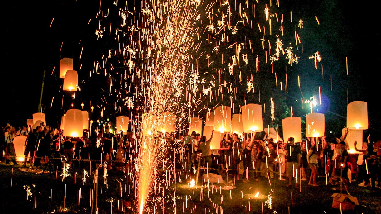 Lanterns and fireworks during Diwali celebration with a crowd at night.