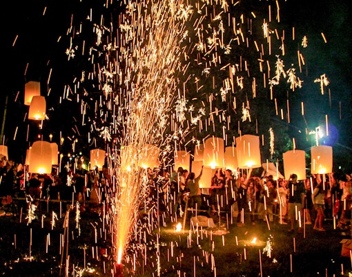 People celebrating Diwali with fireworks and lights in a vibrant street setting.
