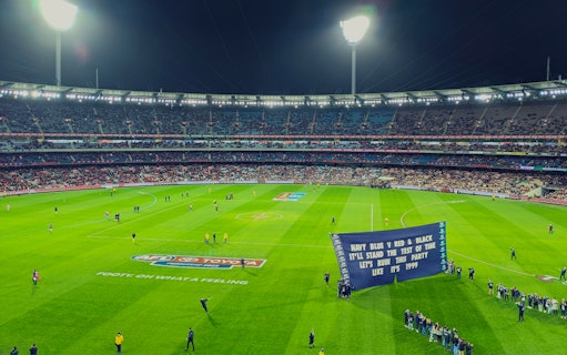 Australian Rules football game at Melbourne Cricket Ground with players and crowd.