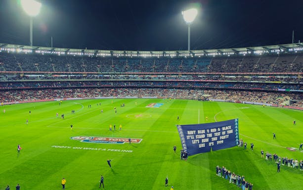 Australian Rules football game at Melbourne Cricket Ground with players and crowd.