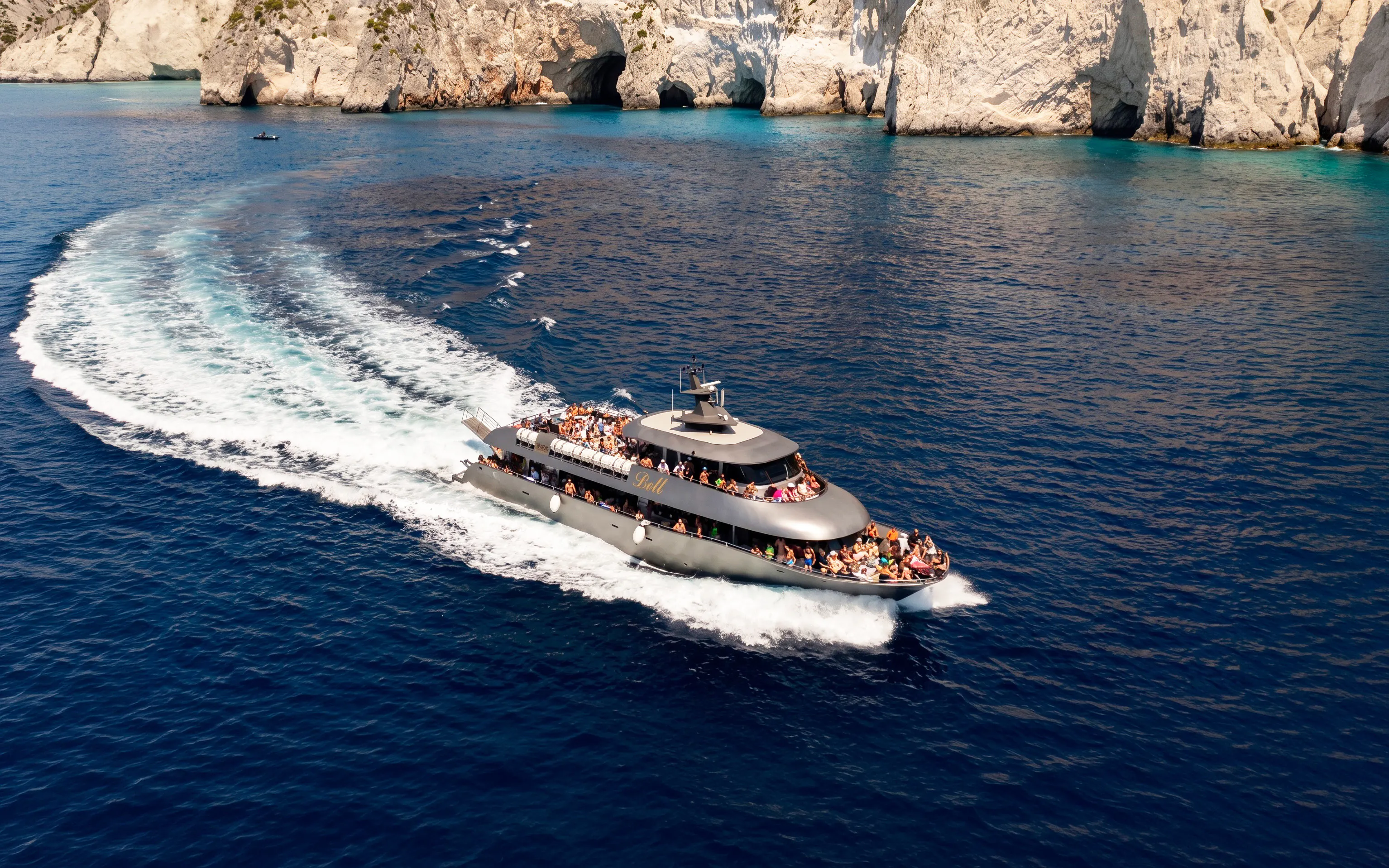 Cruise ship sailing near rocky cliffs on Rhodes to Symi Island tour.