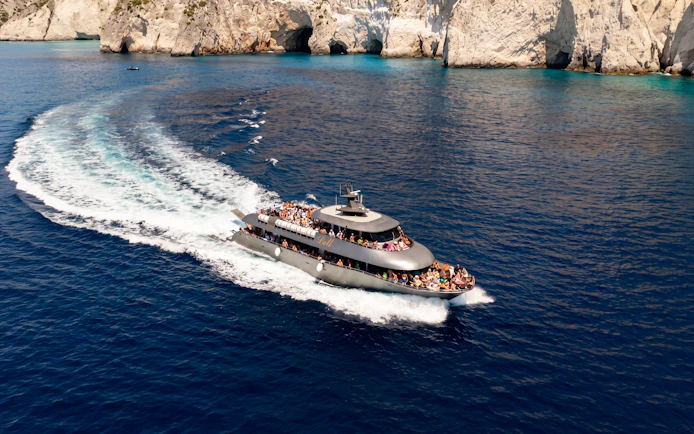 Cruise ship sailing near rocky cliffs on Rhodes to Symi Island tour.