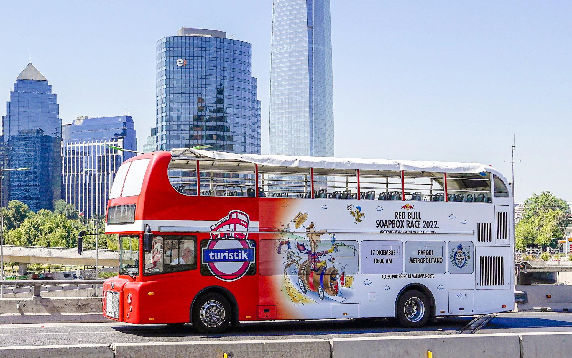 Red double-decker bus on Santiago city tour with skyscrapers in the background.