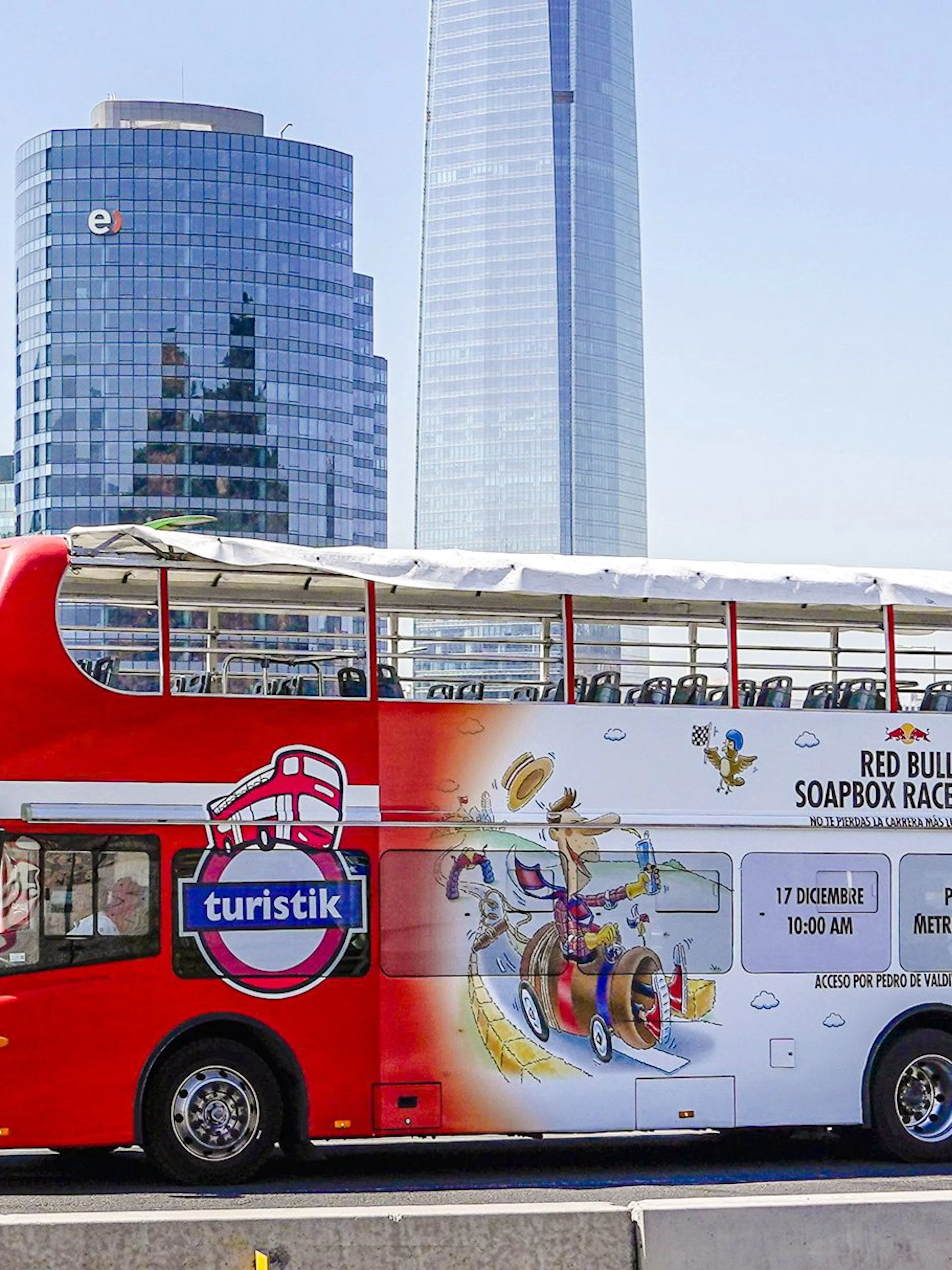 Red double-decker bus on Santiago city tour with skyscrapers in the background.