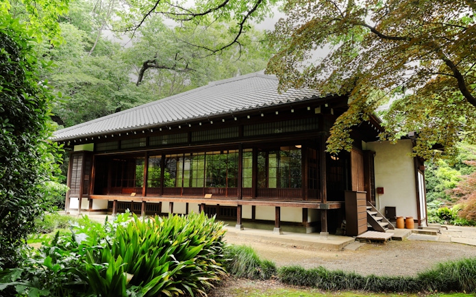 Historic Okyokan tea house in Tokyo National Museum's Japanese Garden, surrounded by lush greenery.