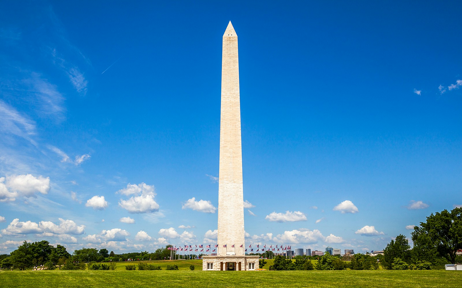 Washington Monument with flags, Washington DC, under clear blue sky.