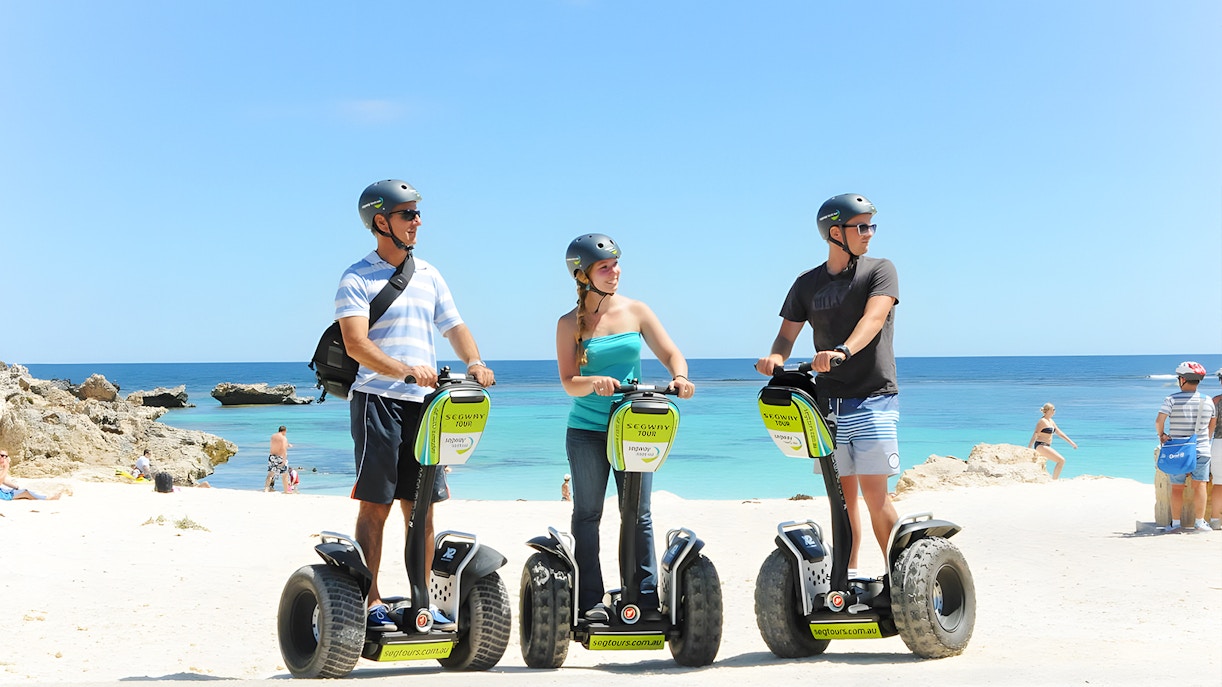 Tourists on Segways at Rottnest Island beach with ocean view.