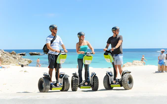 Tourists on Segways at Rottnest Island beach with ocean view.