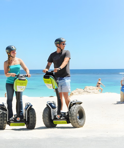 Tourists on Segways at Rottnest Island beach with ocean view.