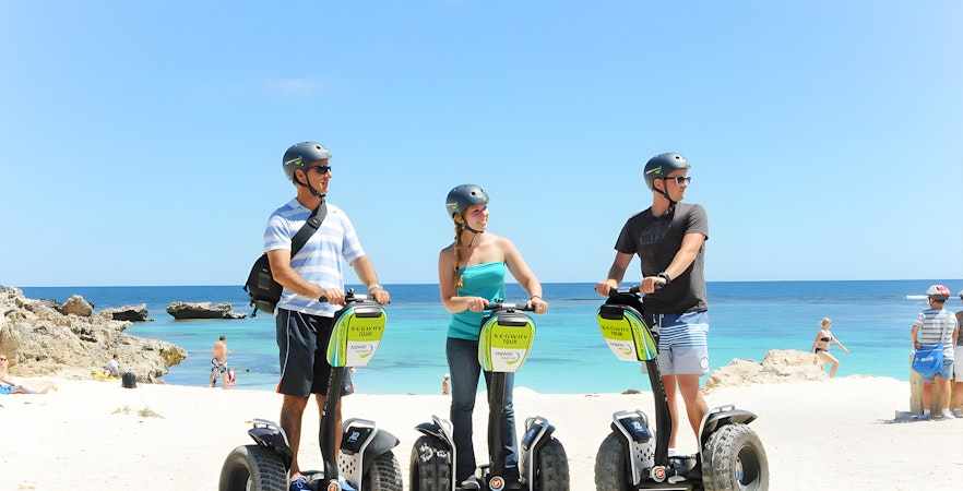 Tourists on Segways at Rottnest Island beach with ocean view.
