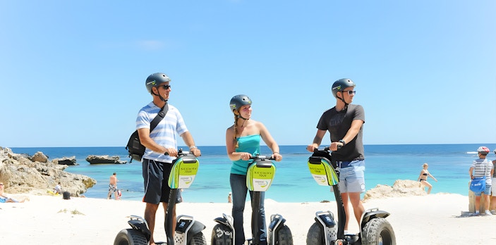 Tourists on Segways at Rottnest Island beach with ocean view.