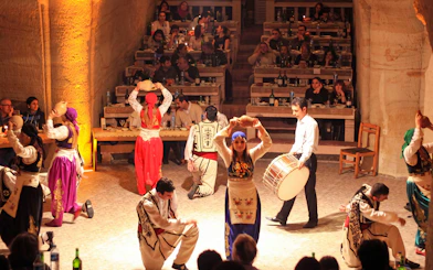 Women in traditional Turkish clothes performing folk dance in a cave restaurant.