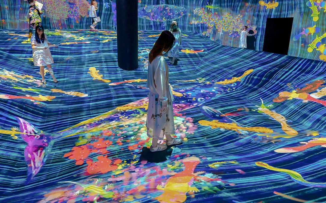 Visitors interacting with digital art projections at teamLab Future Park.
