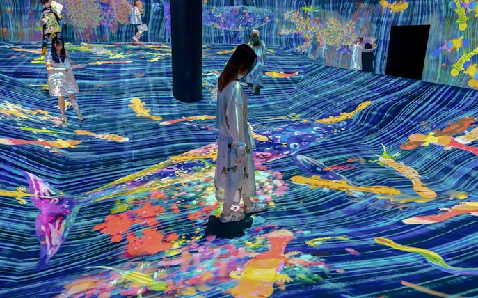 Visitors interacting with digital art projections at teamLab Future Park.