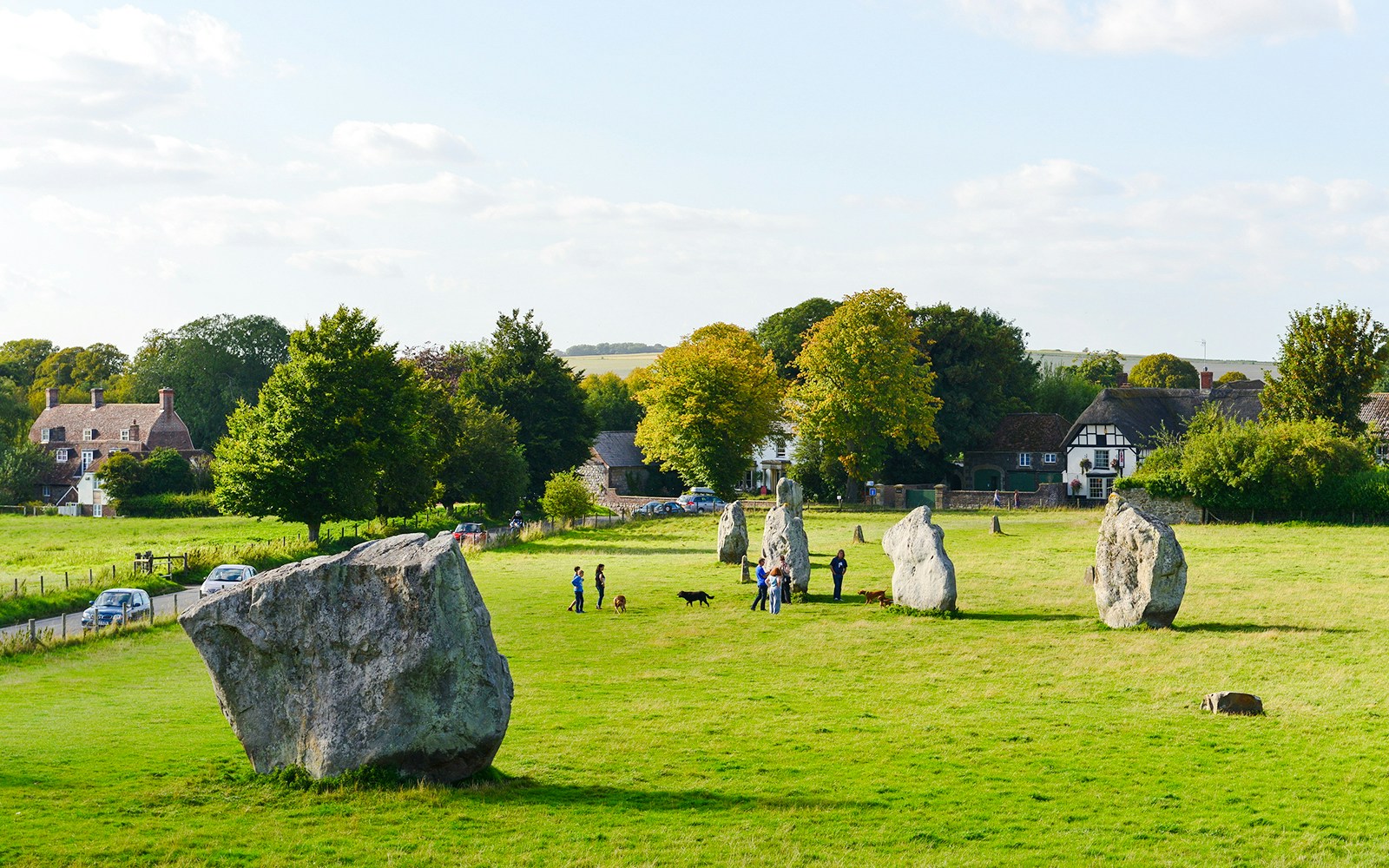 Ancient stone circle with visitors and countryside near Stonehenge, London.