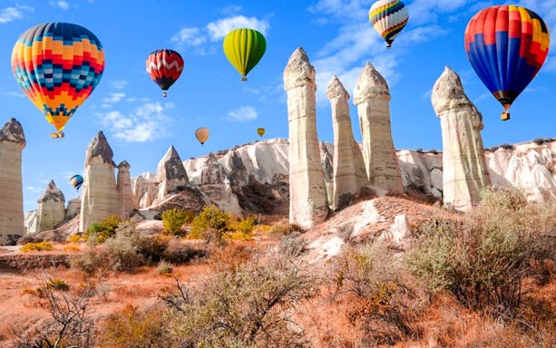 Hot air balloons over Love Valley rock formations at sunrise, Cappadocia horse riding tour.