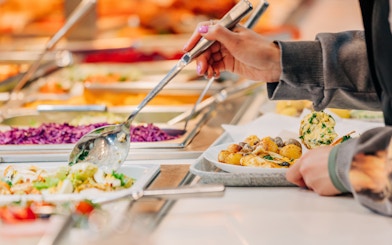 Serving food at buffet in Vibes Bar & Kitchen with various dishes.