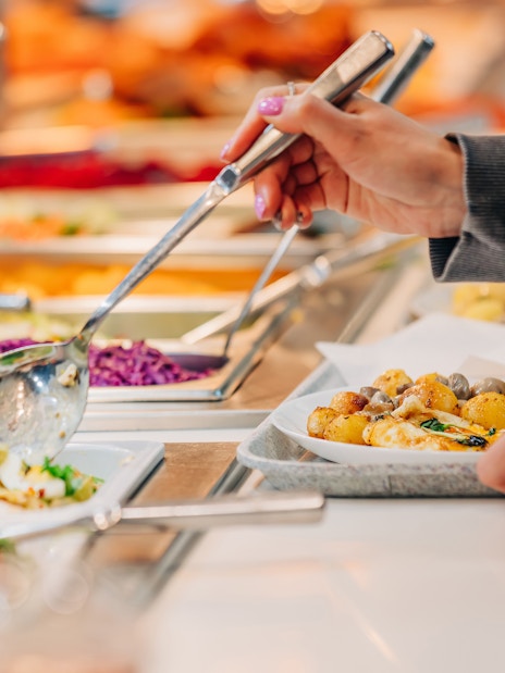 Serving food at buffet in Vibes Bar & Kitchen with various dishes.