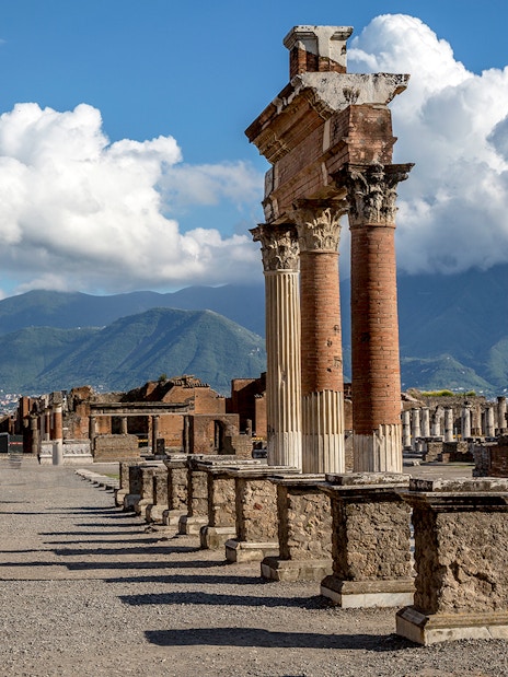 Guided tour group at Pompeii ruins with Mt. Vesuvius in background, near Naples.