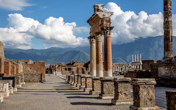 Guided tour group at Pompeii ruins with Mt. Vesuvius in background, near Naples.