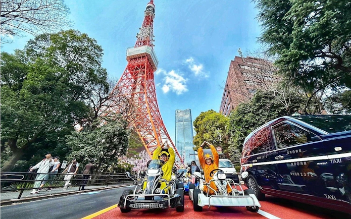 Tourists in costumes driving go-karts near Tokyo Tower.