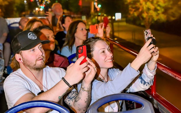 Tourists taking photos on a night Big Bus Tour in Las Vegas.