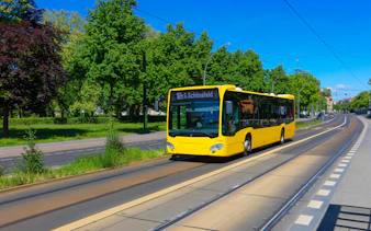 BVG Berlin bus on a tree-lined street heading to Schönefeld.