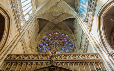 Stained glass rose window and vaulted ceiling inside Saint Vitus Cathedral, Prague.