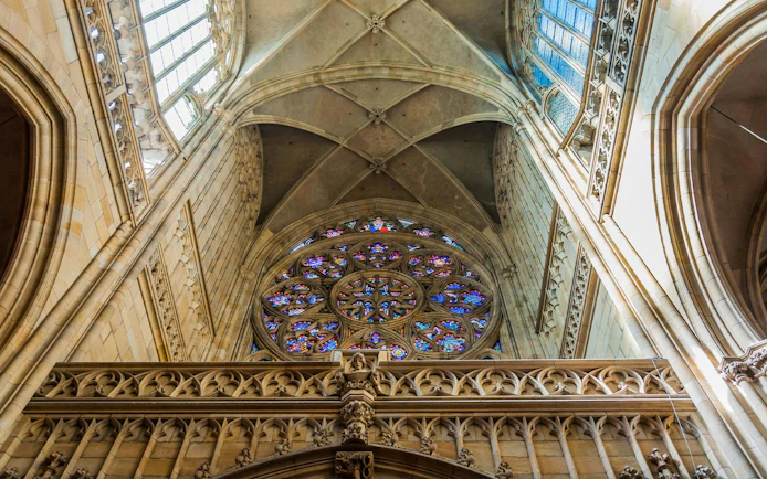 Stained glass rose window and vaulted ceiling inside Saint Vitus Cathedral, Prague.