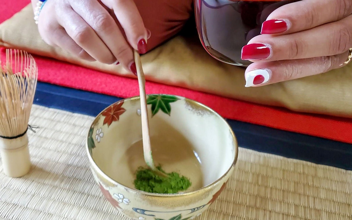 Preparing matcha in a traditional bowl during a tea ceremony in Kyoto.