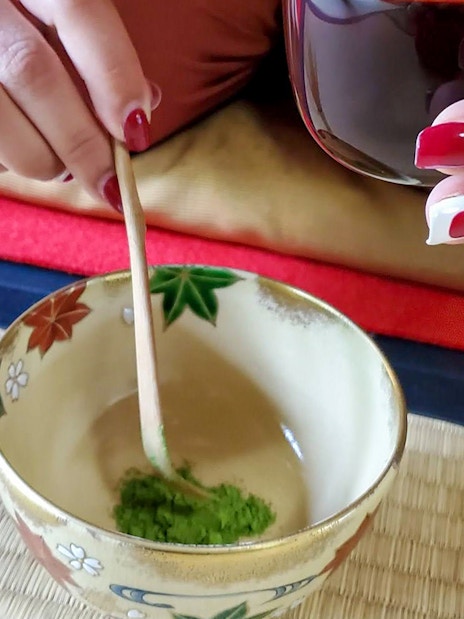 Preparing matcha in a traditional bowl during a tea ceremony in Kyoto.