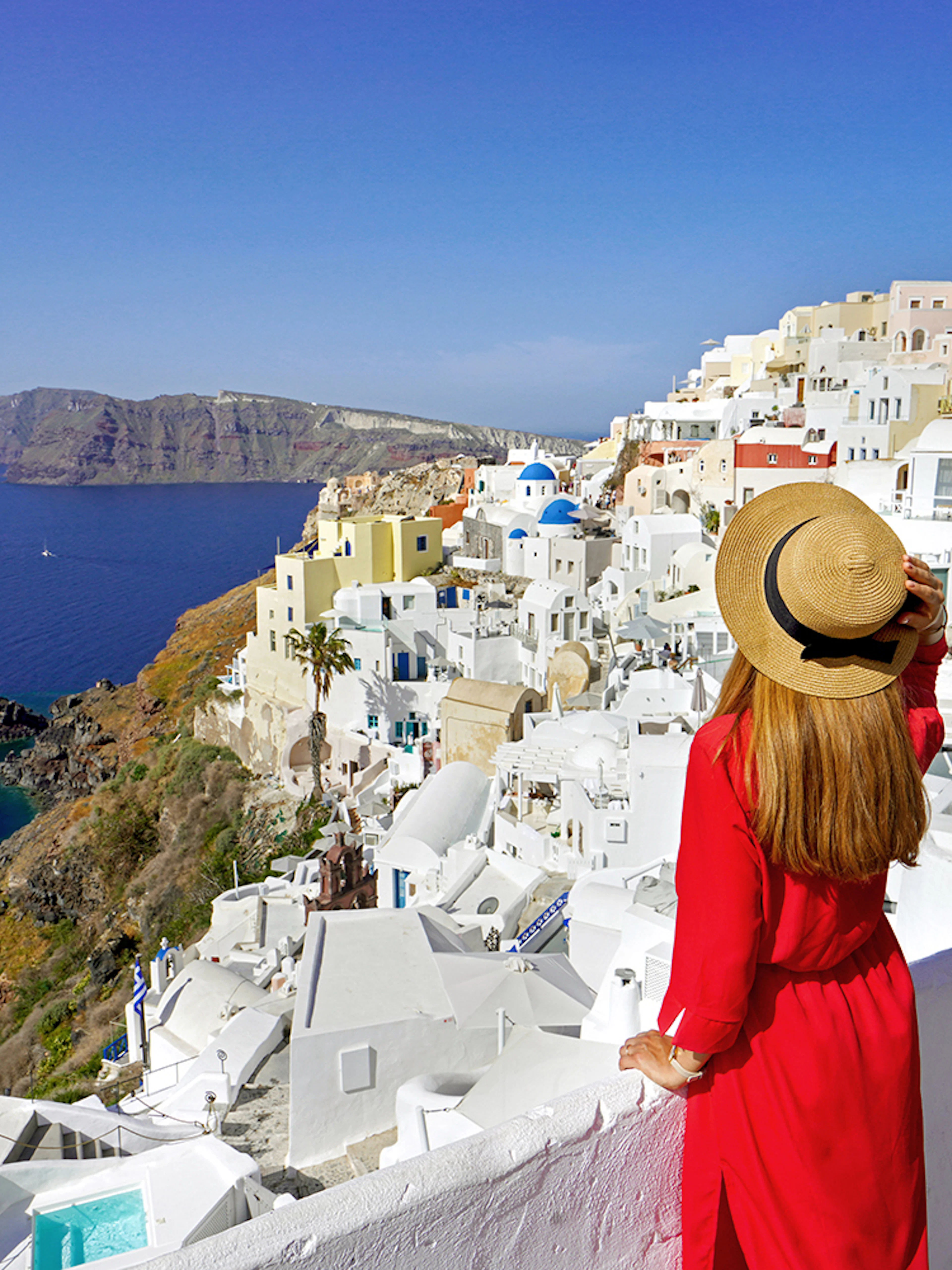 Woman overlooking white buildings and sea in Mykonos, Greece, during a guided day trip from Athens.