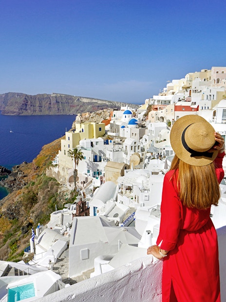 Woman overlooking white buildings and sea in Mykonos, Greece, during a guided day trip from Athens.