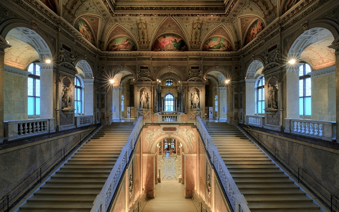 Staircase with ornate ceiling and statues inside Natural History Museum Vienna.