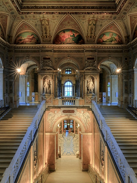 Staircase with ornate ceiling and statues inside Natural History Museum Vienna.