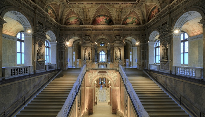 Staircase inside Natural History Museum Vienna with ornate architecture and visitors exploring exhibits.
