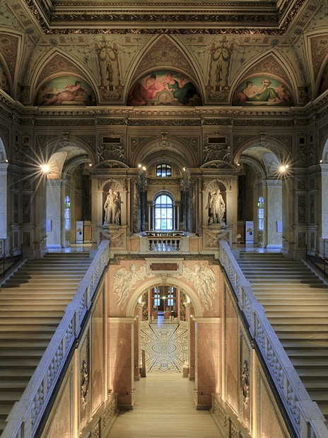 Staircase with ornate ceiling and statues inside Natural History Museum Vienna.