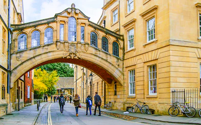 Pedestrians walking under the Bridge of Sighs on the streets of Oxford.