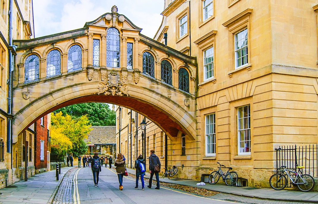 Pedestrians walking under the Bridge of Sighs on the streets of Oxford.