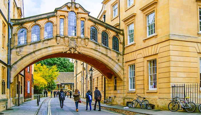 Pedestrians walking under the Bridge of Sighs on the streets of Oxford.