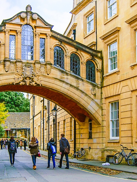 Pedestrians walking under the Bridge of Sighs on the streets of Oxford.
