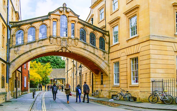 Pedestrians walking under the Bridge of Sighs on the streets of Oxford.
